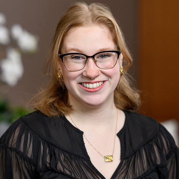 Smiling person with glasses and blonde hair, near About Canadian Honker Restaurant.